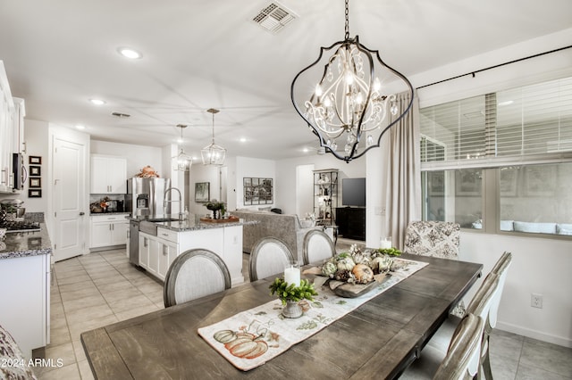 dining area with sink, light tile patterned floors, and a chandelier