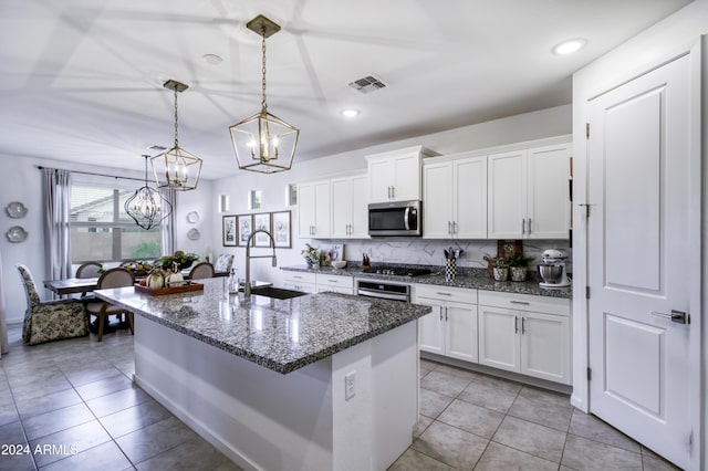 kitchen featuring appliances with stainless steel finishes, decorative light fixtures, white cabinetry, and sink