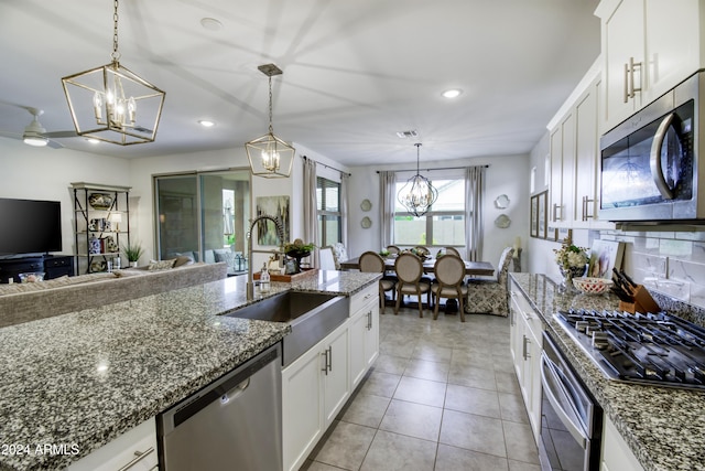 kitchen with sink, white cabinets, decorative light fixtures, and appliances with stainless steel finishes