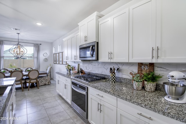 kitchen featuring white cabinetry, backsplash, appliances with stainless steel finishes, and an inviting chandelier