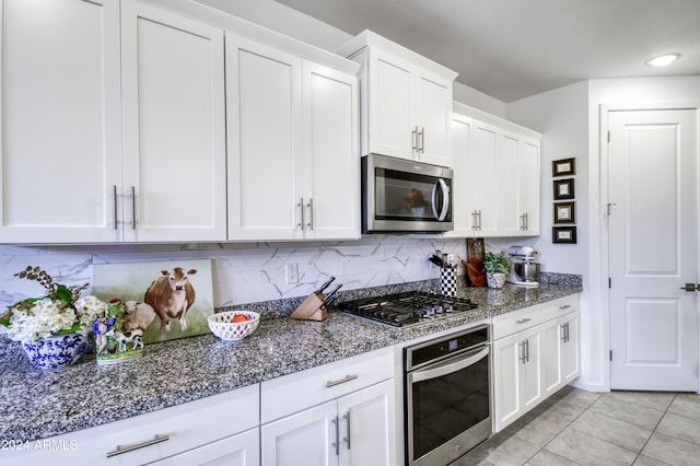 kitchen featuring white cabinets, decorative backsplash, dark stone countertops, and stainless steel appliances