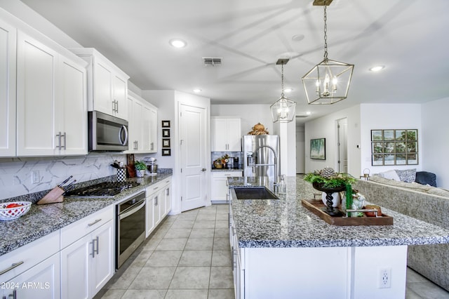 kitchen featuring white cabinetry, sink, hanging light fixtures, stainless steel appliances, and an island with sink