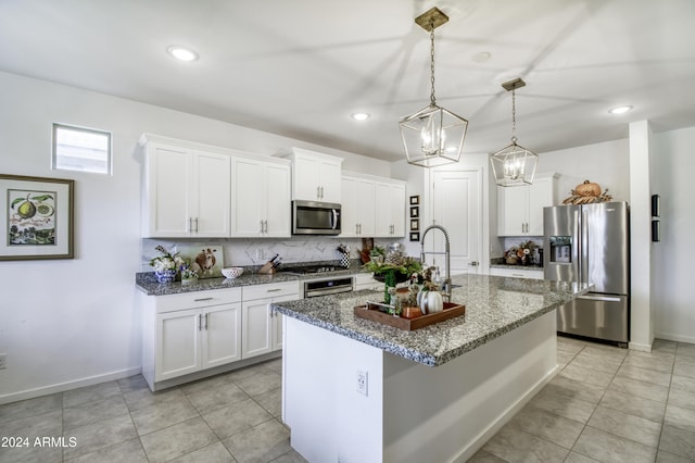 kitchen with pendant lighting, stainless steel appliances, white cabinetry, and a center island with sink