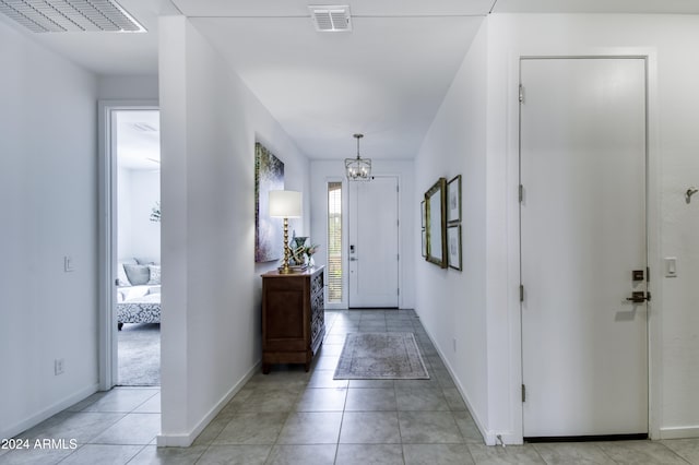 tiled entrance foyer with a notable chandelier