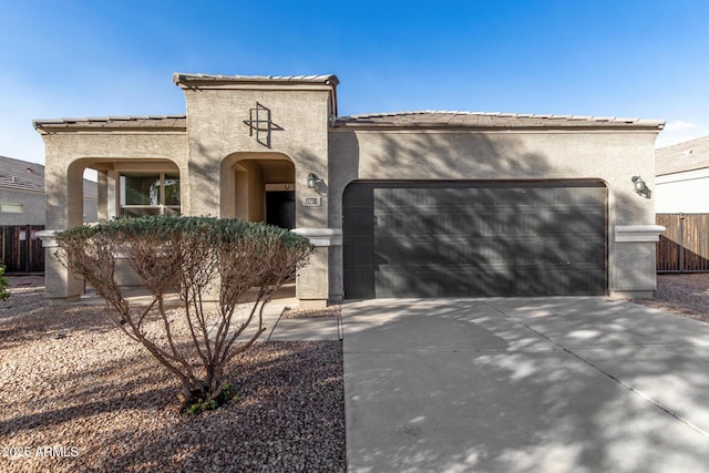 mediterranean / spanish house featuring an attached garage, fence, driveway, a tiled roof, and stucco siding