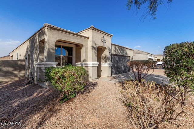 view of front of house with a garage, fence, and stucco siding