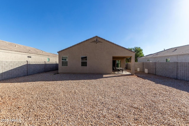 back of house with a fenced backyard, a patio, and stucco siding