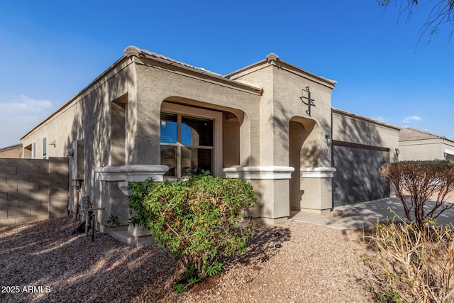 view of front of house with a garage, fence, and stucco siding