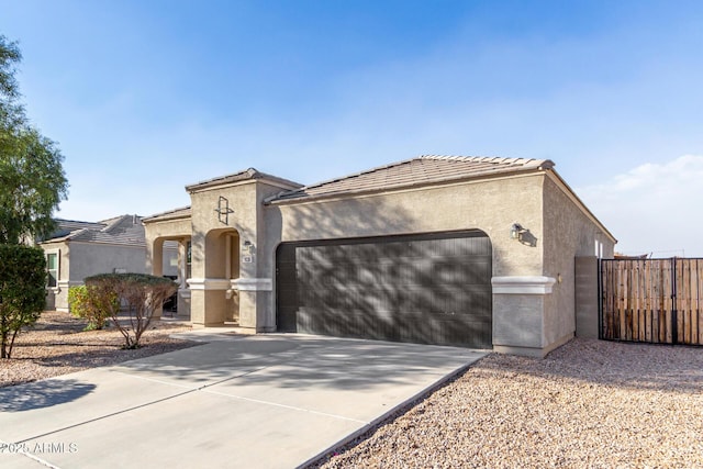 mediterranean / spanish house featuring a garage, driveway, a tile roof, and stucco siding