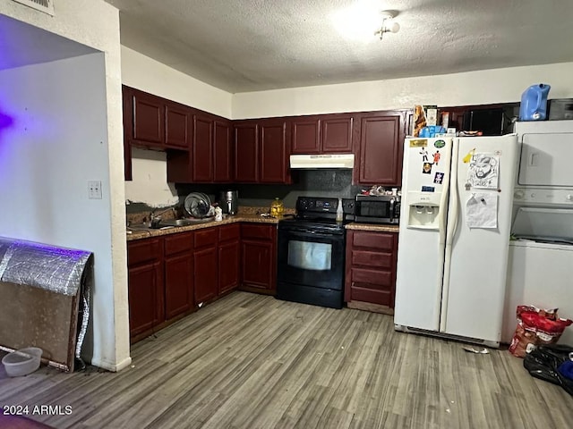 kitchen with white refrigerator with ice dispenser, black electric range, stacked washing maching and dryer, light wood-type flooring, and a textured ceiling