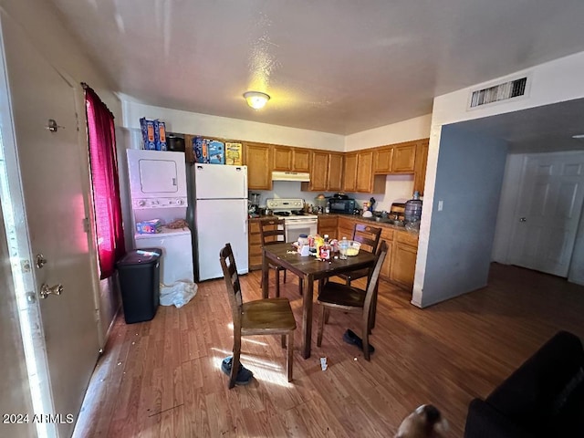 kitchen with hardwood / wood-style floors, white appliances, and stacked washer and clothes dryer