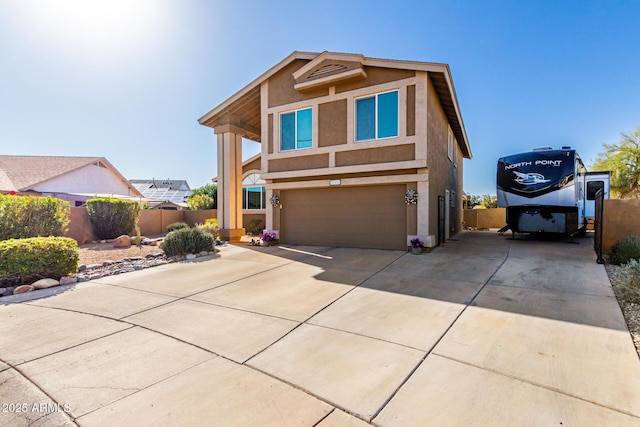 traditional home with stucco siding, an attached garage, concrete driveway, and fence