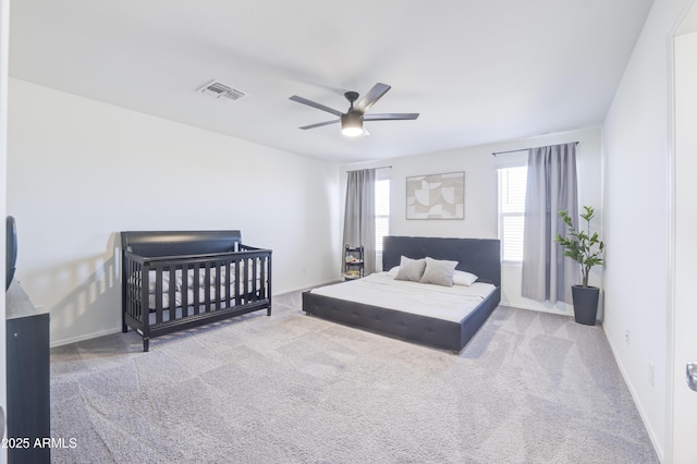 bedroom with ceiling fan, a crib, and carpet floors