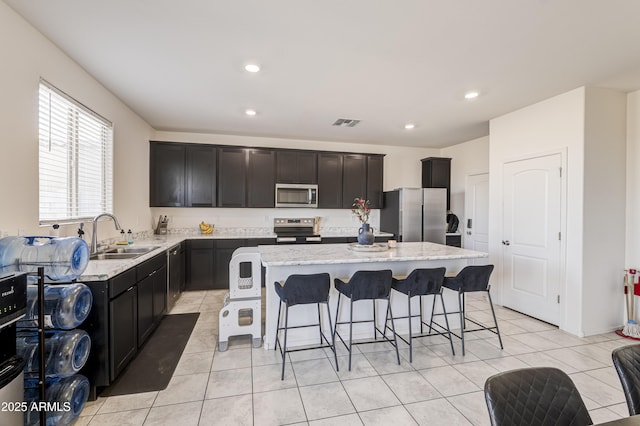 kitchen featuring sink, light tile patterned floors, a center island, and stainless steel appliances