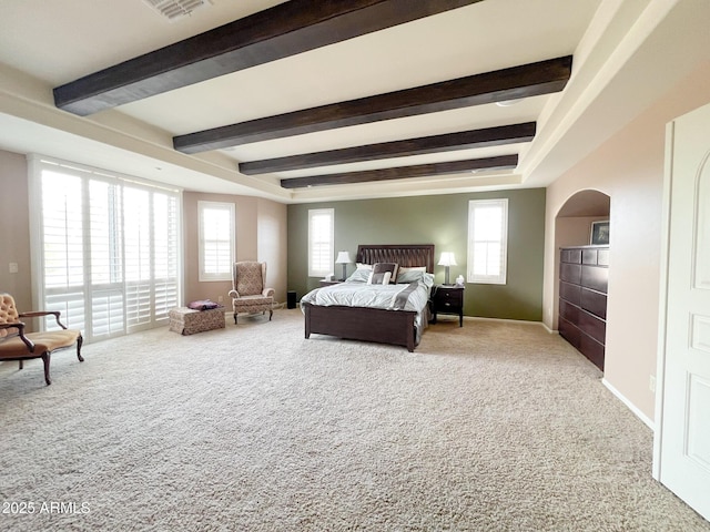 carpeted bedroom with arched walkways, beam ceiling, visible vents, and baseboards