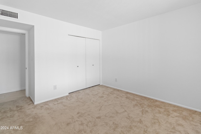 unfurnished bedroom featuring a closet and light colored carpet