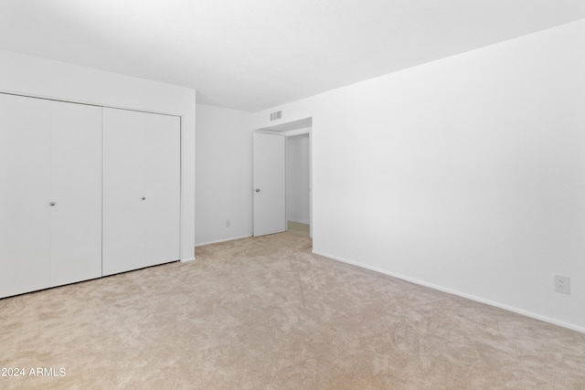 unfurnished bedroom featuring light carpet and a closet