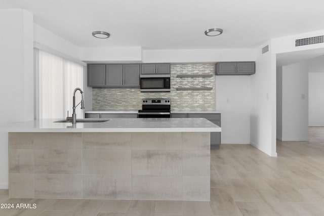 kitchen with sink, gray cabinets, stainless steel appliances, and backsplash