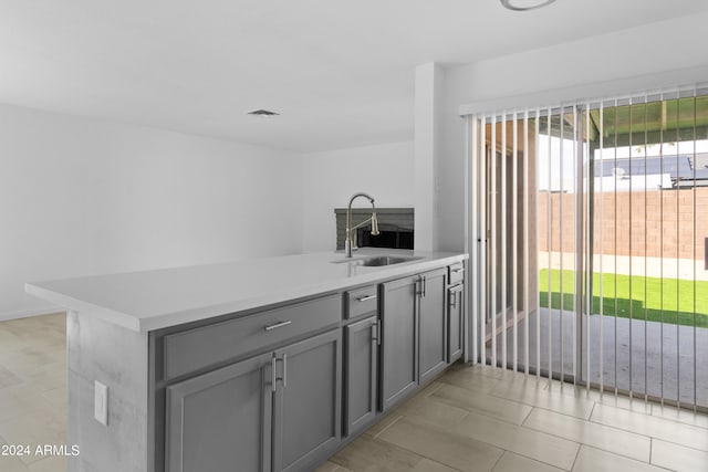 kitchen featuring gray cabinets, light tile patterned floors, sink, and kitchen peninsula