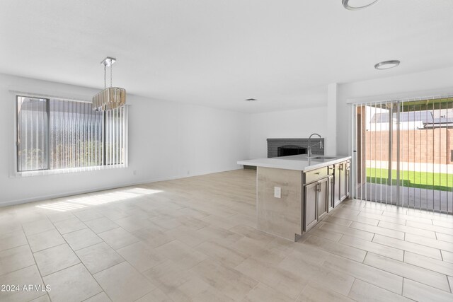 unfurnished living room with light tile patterned flooring, a fireplace, sink, and an inviting chandelier