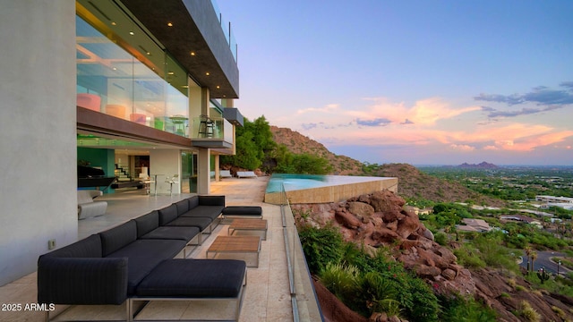 pool at dusk with a mountain view, an outdoor hangout area, and a patio area