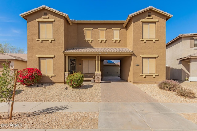 mediterranean / spanish-style home with a tiled roof, decorative driveway, and stucco siding