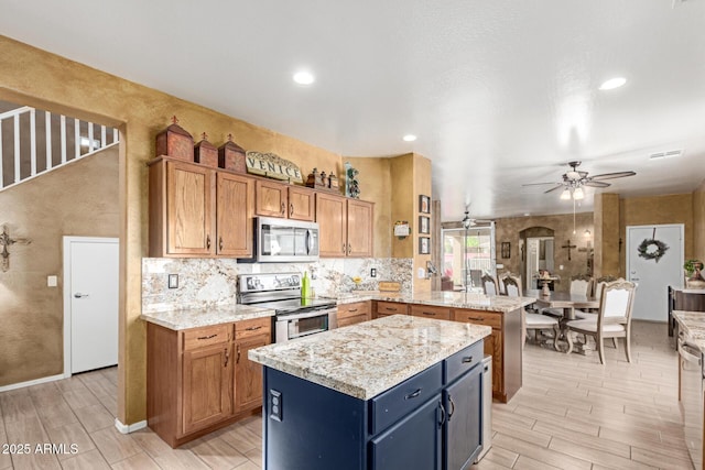 kitchen featuring arched walkways, ceiling fan, a kitchen island, appliances with stainless steel finishes, and a peninsula