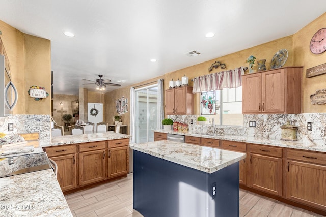 kitchen with brown cabinets, visible vents, decorative backsplash, a sink, and dishwasher