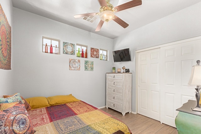 bedroom with a closet, visible vents, ceiling fan, wood finished floors, and baseboards