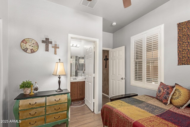 bedroom featuring visible vents, light wood-style floors, a sink, ceiling fan, and ensuite bath