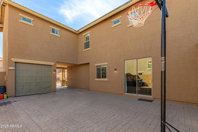 exterior space featuring an attached garage, a patio, and stucco siding