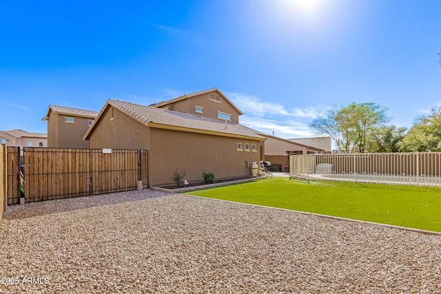 back of house featuring a fenced backyard, a tile roof, a lawn, stucco siding, and a patio area