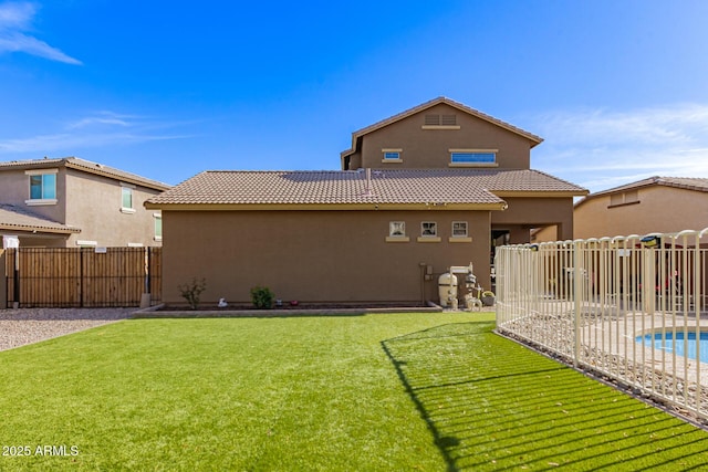 rear view of property with a fenced backyard, a tiled roof, a lawn, and stucco siding