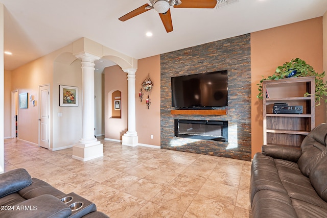 living room featuring a stone fireplace, ornate columns, and ceiling fan