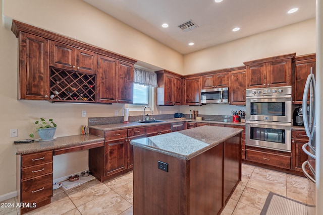 kitchen with sink, a kitchen island, appliances with stainless steel finishes, and stone countertops