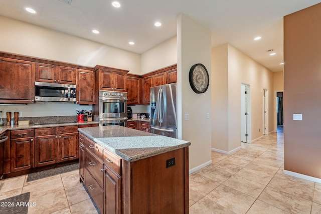 kitchen featuring light stone counters, appliances with stainless steel finishes, and a center island