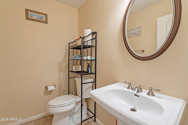 bathroom featuring toilet, sink, and tile patterned flooring