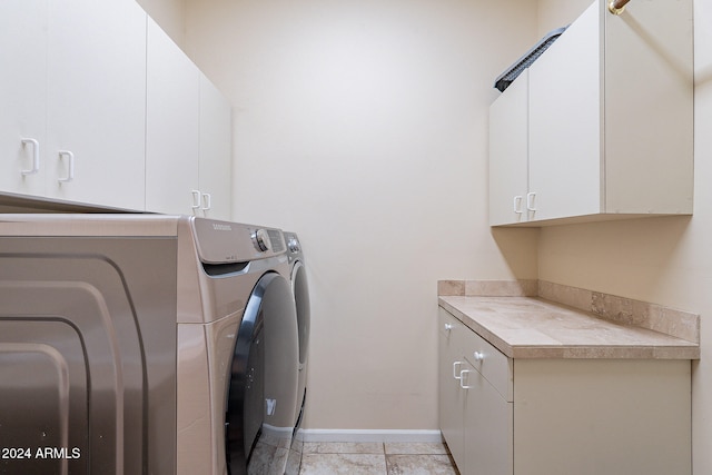 laundry room with washing machine and clothes dryer and cabinets