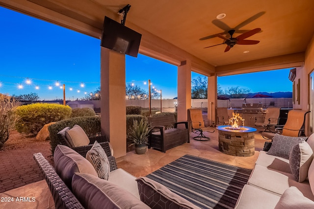 view of patio / terrace featuring ceiling fan and an outdoor living space with a fire pit