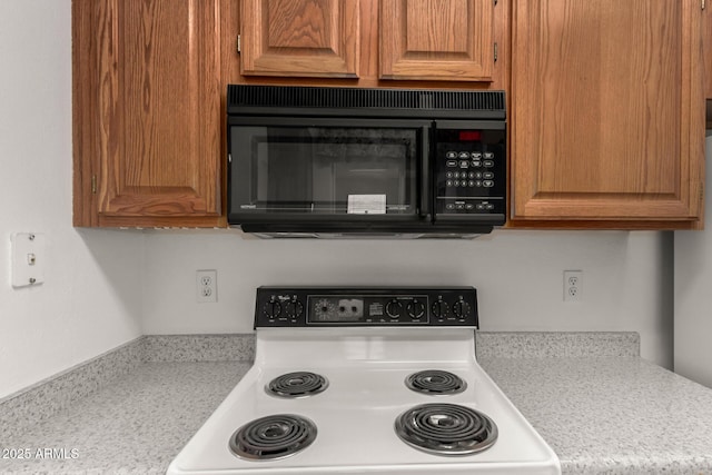 1501 E Colonial Dr, Chandler, AZ 85249 - kitchen with black microwave, light countertops, brown cabinetry, and electric stove