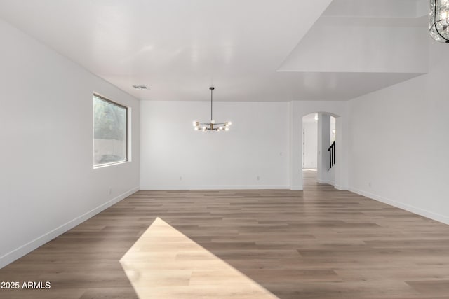 unfurnished room with hardwood / wood-style floors and a notable chandelier