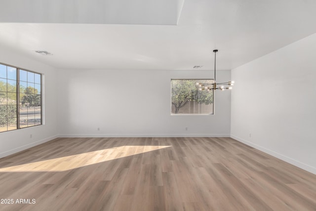 unfurnished room featuring a chandelier and light hardwood / wood-style floors