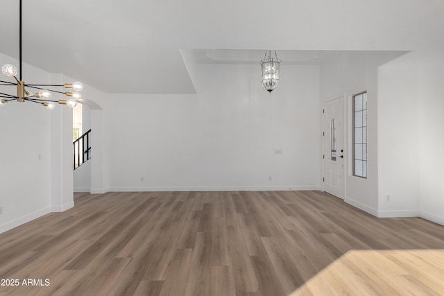 unfurnished living room with wood-type flooring and a chandelier