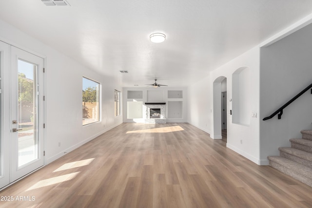 unfurnished living room with ceiling fan, a fireplace, and light hardwood / wood-style floors