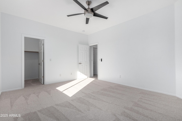 unfurnished bedroom with ceiling fan, a walk in closet, light carpet, and a closet