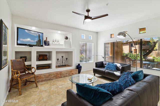 living room featuring built in shelves, ceiling fan, and light tile patterned flooring