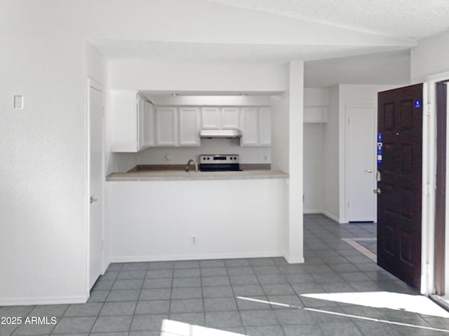 kitchen featuring white cabinetry, lofted ceiling, stainless steel range with electric cooktop, and dark tile patterned flooring