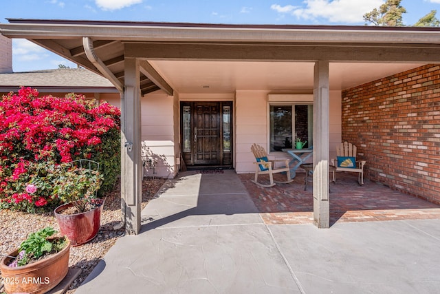 doorway to property with covered porch and brick siding