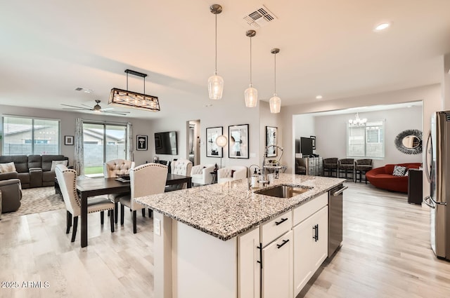 kitchen with open floor plan, appliances with stainless steel finishes, light stone countertops, and white cabinets