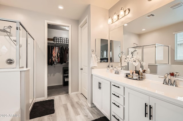 bathroom with a stall shower, a walk in closet, a sink, and double vanity